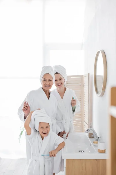 Cheerful Lesbian Parents Bathrobes Holding Toothbrushes Daughter Bathroom — Stock Photo, Image