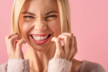 Sarışın, kaşlarını çatan ve pembe renkte sırıtan kadını yakından çek. 