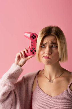 KYIV, UKRAINE - 29 Ekim 2021: Pembe üzerine izole edilmiş joystick tutan üzgün kadın 