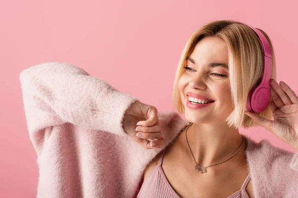 Positieve Blonde Vrouw Luisteren Muziek Draadloze Hoofdtelefoon Geïsoleerd Roze — Stockfoto