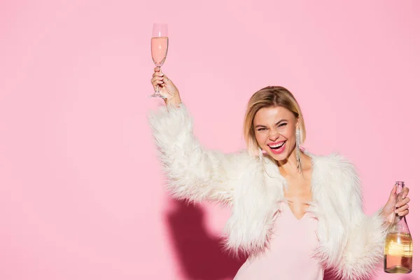 Excited Blonde Woman Slip Dress Faux Fur Jacket Holding Bottle — Stock Photo, Image