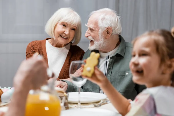 Vrolijk Meisje Houden Koekje Buurt Gelukkig Grootouders Wazig Moeder Gieten — Stockfoto