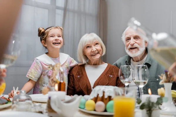 Vrolijk Meisje Glimlachen Buurt Gelukkig Grootouders Feestelijk Diner Tafel — Stockfoto