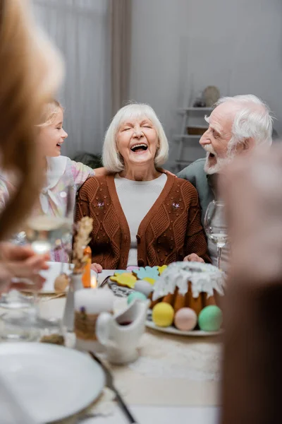 Mujer Mayor Riendo Con Los Ojos Cerrados Cerca Familia Cena —  Fotos de Stock