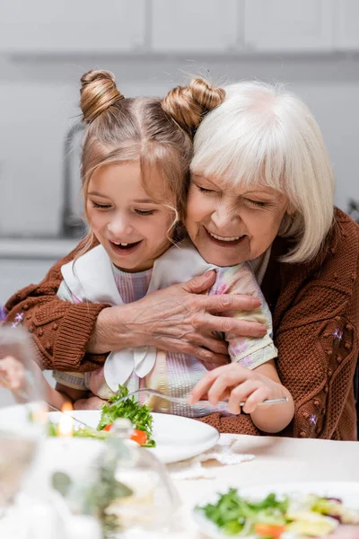 Happy Senior Woman Embracing Granddaughter Eating Vegetable Salad Easter Dinner — Stock Photo, Image