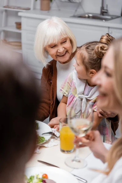 cheerful senior woman hugging granddaughter while celebrating easter with family