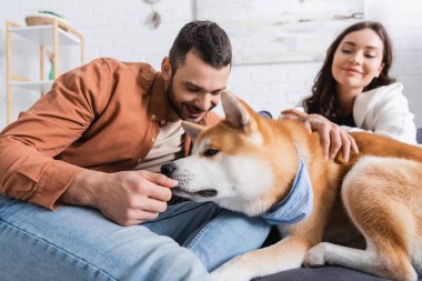 Bulanık kadının yanında mutlu bir adamın eli kokan köpek.