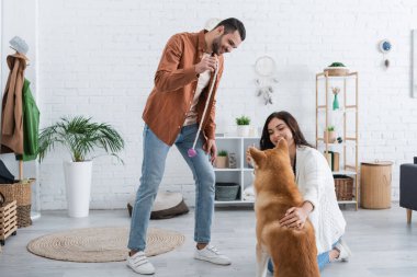 Genç bir kadın, Akia Inu köpeğine sarılıyor. Yanında da gülümseyen bir erkek arkadaş.