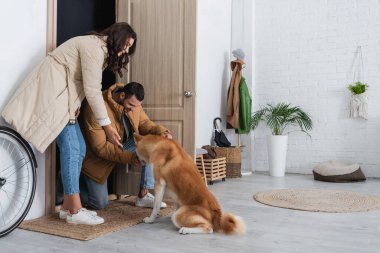 Kışlık ceketli, gülümseyen bir çift Akita Inu köpeğinin yanında duruyor.