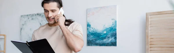 Hombre Hablando Por Teléfono Móvil Sosteniendo Cuaderno Casa Bandera — Foto de Stock