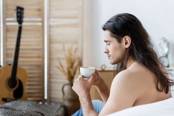 長髪の長髪の男がコーヒーを飲みながら — ストック写真