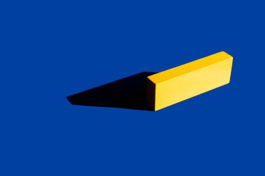 bright yellow tetragonal block on blue background with shadow, ukrainian concept clipart