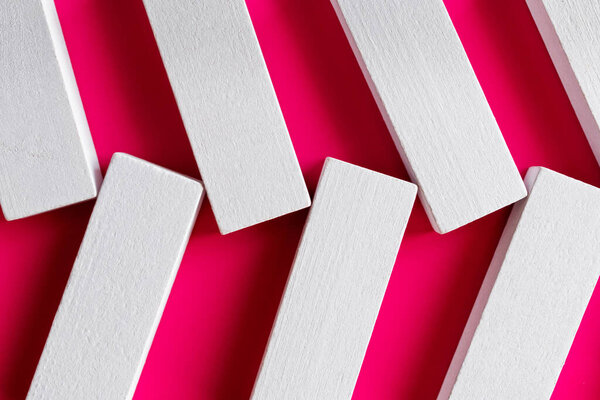 close up of white quadrangular blocks on pink background, top view