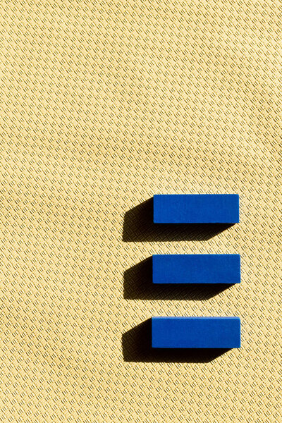 top view of three blue blocks on beige textured background