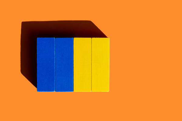top view of colorful blue and yellow blocks on orange background, ukrainian concept