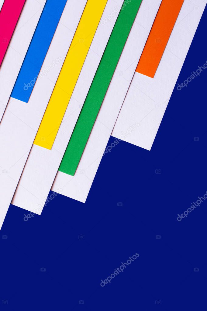 multicolored diagonal paper stripes on blue background with copy space