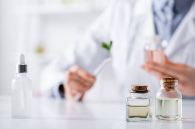 Serumun yanında gerekli yağları olan şişeler ve laboratuvarda bulanık kimyagerler.