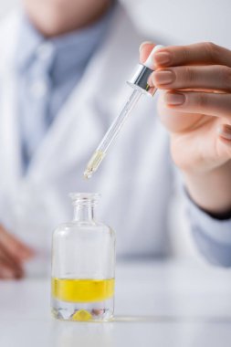 Laboratuvar asistanının şişenin yanında serumla pipet tutarken çekilmiş görüntüsü.