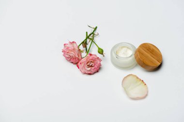 Beyaz kremalı konteynırın yanında pembe çiçekler