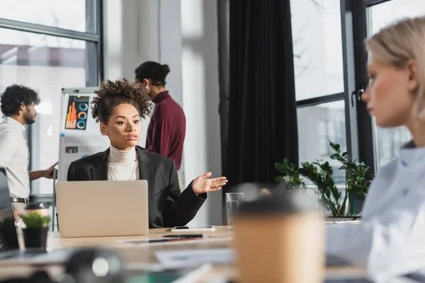 Mujer Negocios Afroamericana Hablando Con Colega Borroso Cerca Gadgets Oficina — Foto de Stock