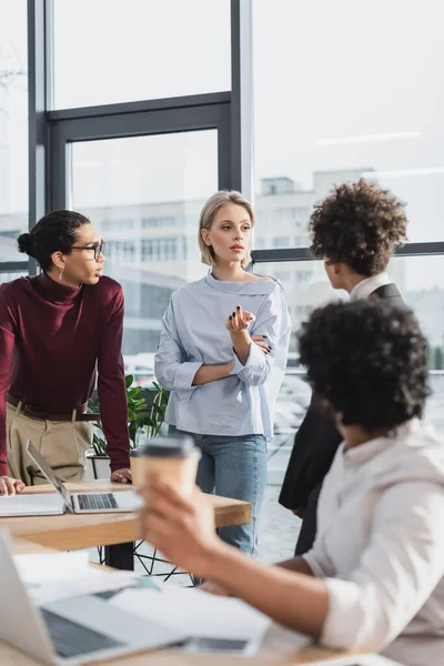 Junge Geschäftsfrau Gespräch Mit Multiethnischen Kollegen Der Nähe Von Zeitungen — Stockfoto