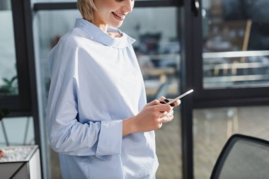 Ofiste cep telefonu kullanan gülümseyen iş kadını manzarası 