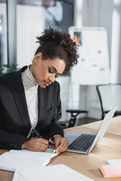 Afrikai Amerikai Üzletasszony Írásban Notebook Közelében Laptop Papírok Irodában — Stock Fotó