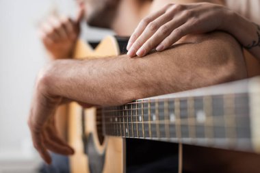 Akustik gitarın yanında, erkek arkadaşının koluna dokunan kadın görüntüsü. 