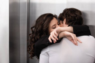 curly woman with closed eyes kissing man near elevator  clipart