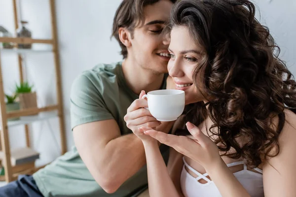 Fröhlicher Mann Küsst Glückliche Freundin Mit Tasse Kaffee — Stockfoto