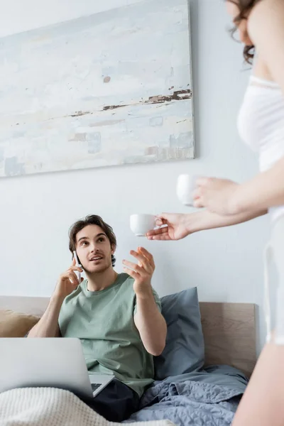 Mulher Desfocada Dando Xícara Café Para Namorado Falando Smartphone Enquanto — Fotografia de Stock