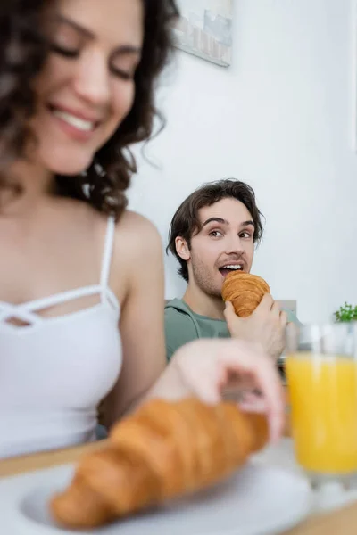 Homem Comendo Croissant Olhando Para Mulher Feliz Borrada — Fotografia de Stock