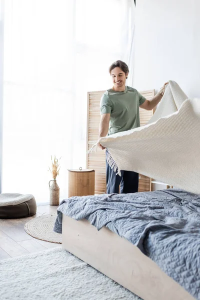 Feliz Joven Cubriendo Cama Con Manta — Foto de Stock