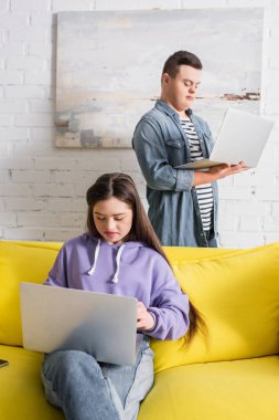 Evde arkadaşının yanında dizüstü bilgisayar kullanan Down sendromlu bir genç kız. 