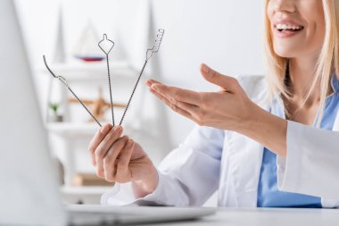 Bilgisayardaki görüntülü sohbet sırasında logopedik sondalara işaret eden neşeli konuşma terapistinin kırpılmış görüntüsü 
