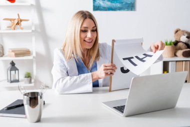 Danışma odasındaki dizüstü bilgisayardan gelen mektuplarla dolu neşeli bir logopedici. 