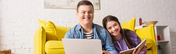 Sonriente Adolescente Sosteniendo Portátil Cerca Novia Con Cuaderno Casa Pancarta —  Fotos de Stock