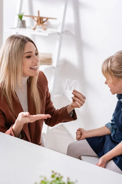 Gülümseyen Konuşma Terapisti Danışma Odasındaki Çocuğun Yanındaki Mektuba Işaret Ediyor — Stok fotoğraf