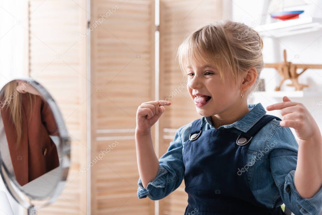 Pupil pointing with fingers while talking near mirror during speech therapy in classroom