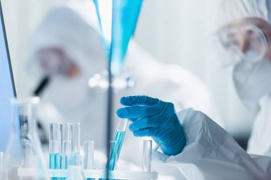 Laboratuvarda test tüpleriyle çalışan lateks eldivenli bulanık biyomühendis.