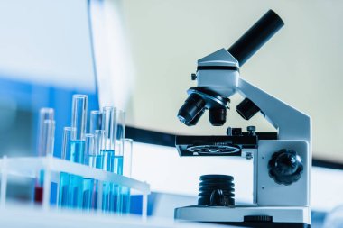 Laboratuvardaki test tüplerinin yakınındaki mikroskobun seçici odak noktası