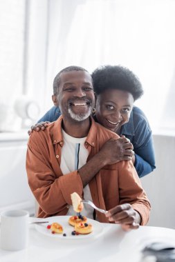 Neşeli ve yaşlı Afrikalı Amerikalı çift kahvaltıda kameraya bakıyor. 