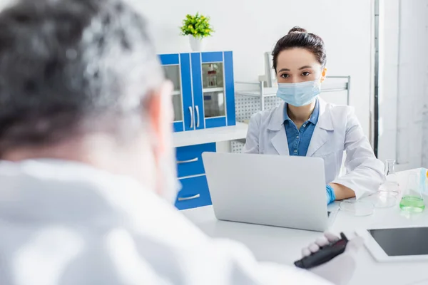 Young Scientist Medical Mask Working Laptop Blurred Colleague — Stock Photo, Image