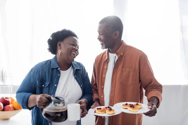 Χαρούμενος Αφροαμερικάνος Που Κρατάει Πιάτα Τηγανίτες Κοντά Στη Γυναίκα Του — Φωτογραφία Αρχείου
