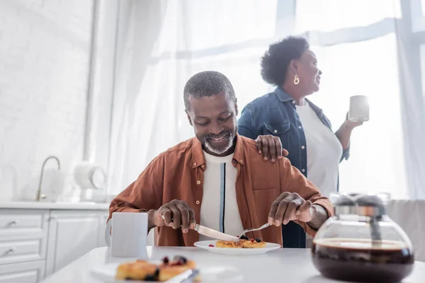 senior african american man having breakfast near happy wife