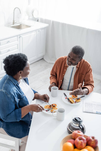high angle view of senior african american man talking with wife during breakfast 