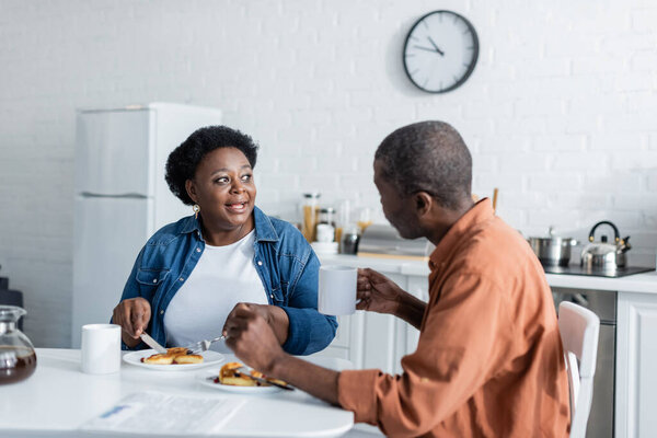 senior african american woman talking with husband during breakfast at home