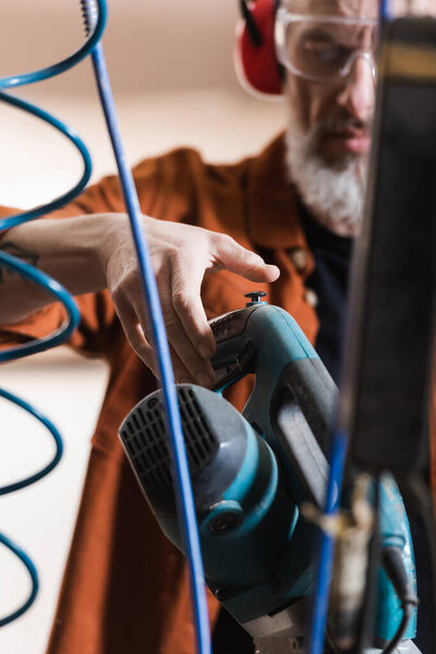 обрезанный вид размытого плотника, работающего с ротором в мастерской