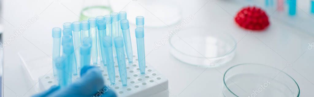 cropped view of hand near test tubes on desk in laboratory, banner