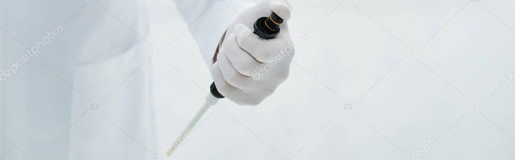 partial view of scientist in latex glove holding micropipette, banner